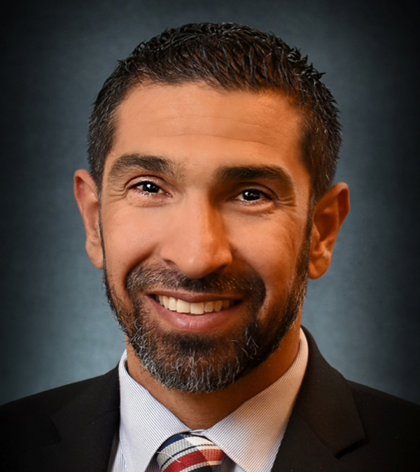 A smiling man with a beard wearing a tie, exuding confidence and professionalism.