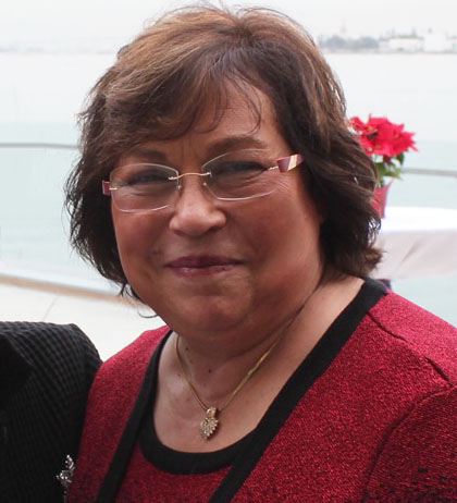 A woman wearing glasses and a red sweater, smiling warmly at the camera.